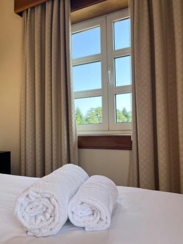 two towels on a bed in front of a window at Casas do Souto in Lousada