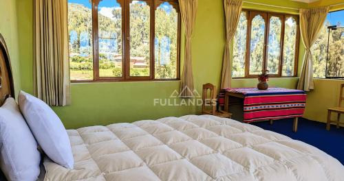 a bedroom with a large white bed with windows at Amantani sol Andino in Amantani