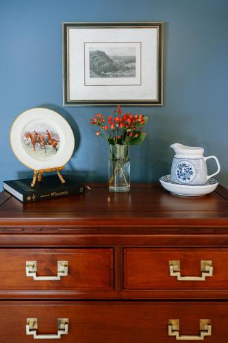 a wooden dresser with a vase of flowers on top of it at The Rochester Inn in Sheboygan Falls