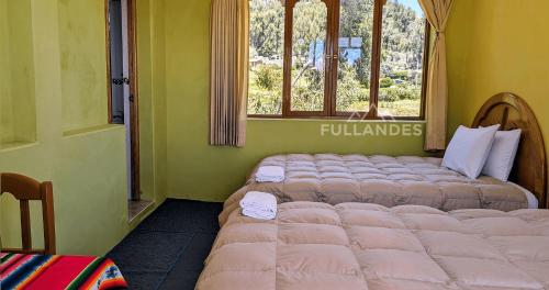 two beds sitting in a room with a window at Amantani sol Andino in Amantani