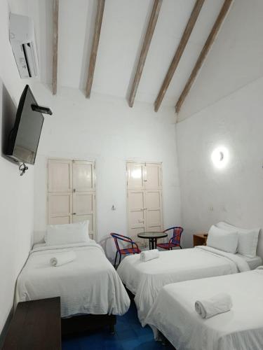 three beds in a room with a tv and a table at Zana Hotel Boutique in Cartagena de Indias