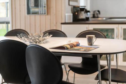 a table with black chairs and a cup of coffee on it at BV313-Blavand-Hvidbjerg-Strandvej-40 in Blåvand