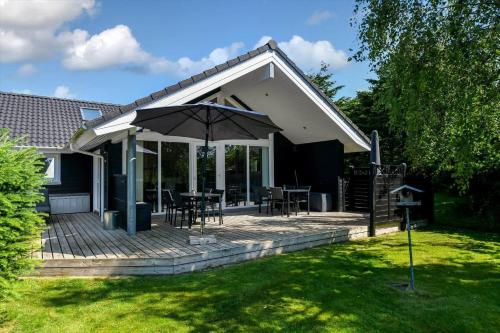 a patio with an umbrella and tables and chairs at BV313-Blavand-Hvidbjerg-Strandvej-40 in Blåvand