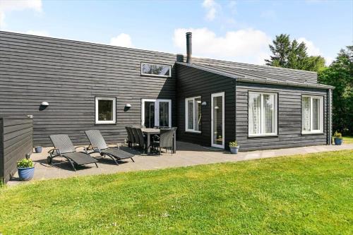 a black house with a patio and a table and chairs at BV269-Blavand-Hvidbjerg-Strandvej-25-A in Blåvand