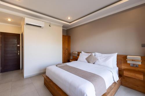 a bedroom with a large bed with white sheets at Sandat Living in Canggu