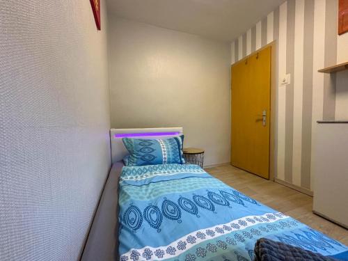 a small bedroom with a bed with a blue comforter at Knusperhäuschen in Waldau