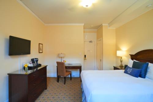 a hotel room with a bed and a desk and a television at University Club of San Francisco in San Francisco