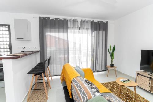un salon avec un canapé et une cuisine dans l'établissement Le Nid de Thalys - Charming Apartment, à Cayenne