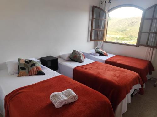 una camera con tre letti con lenzuola rosse e una finestra di Cantinho do mumu a Ouro Preto