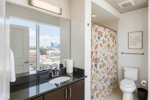 um banheiro com uma pia, um vaso sanitário e uma janela em 2 bedroom downtown highrise em Raleigh
