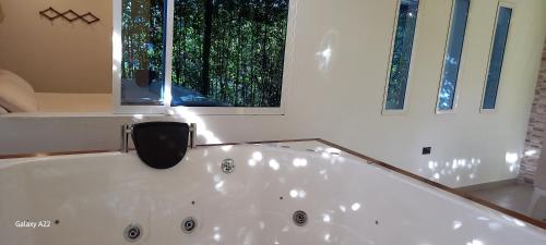 a white bath tub in a bathroom with two windows at Hotel y Cabañas Parinzzi in Guatapé