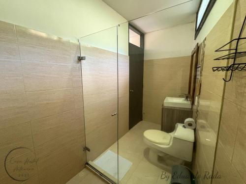 a bathroom with a toilet and a glass shower at Hostal Antawara Tayrona in El Zaino