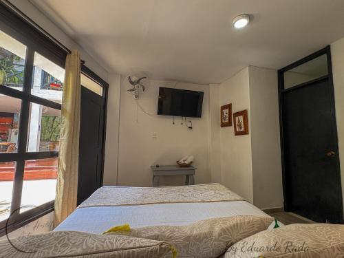 a bedroom with a bed and a tv on the wall at Hostal Antawara Tayrona in El Zaino