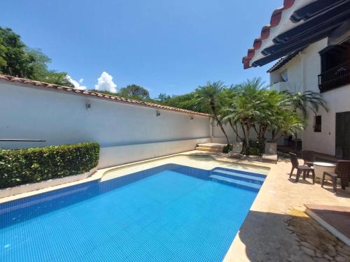 a swimming pool next to a white building with trees at Espectacular Casa en Cauca viejo con piscina, jacuzzi y turco in Jericó