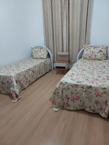 a bedroom with two beds and a table and a chair at Pousada Jardim Alterosa in Vespasiano