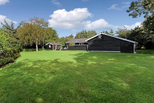 a large yard with a black house in the background at BV276-Blavand-Sonder-Vasevej-150 in Blåvand