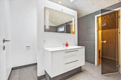 een badkamer met een witte wastafel en een spiegel bij 0200-Romo-Elmegardsvej-10 in Tagholm
