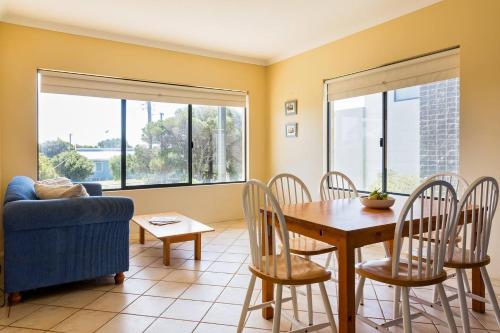 a living room with a blue couch and a table and chairs at Breakaway - Bay Views Games and Beach Bliss in Gracetown