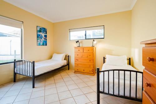 a bedroom with two beds and a dresser and a window at Breakaway - Bay Views Games and Beach Bliss in Gracetown