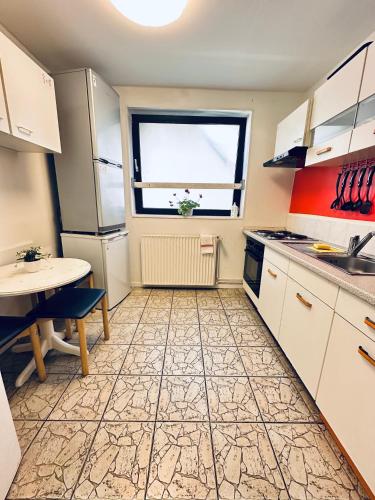 a kitchen with white cabinets and a table and a window at Hostel Pinneberg in Pinneberg