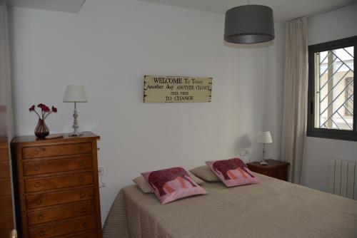a bedroom with a bed and a dresser with two pillows at Apartamento Flavia I Espalter in Sitges