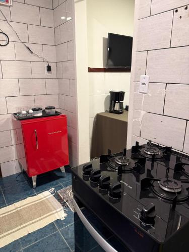 a kitchen with a black stove and a red cabinet at Hospedagem no centro da cidade! in Macaé