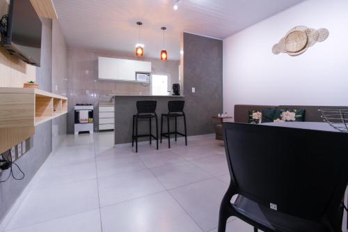 a kitchen with a counter and stools in a room at LOFT PAJUMAR 1 ANDAR 300mt PRAIA PAJUCARA in Maceió