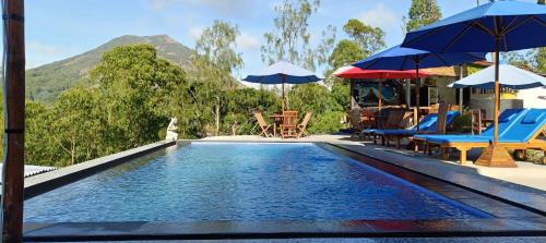 a swimming pool with chairs and umbrellas next to a resort at Bali Cottages Lake View in Kintamani