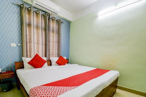a bedroom with a bed with red pillows at Hotel O The Dove Villa in Dispur