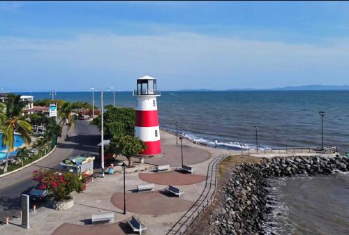 a red and white lighthouse sitting next to the ocean at Casa del Pacífico en Puntarenas Centro con parqueo in Puntarenas