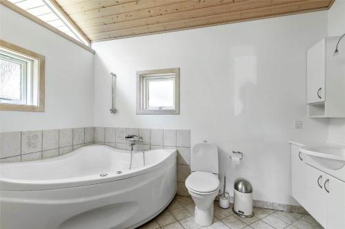 a white bathroom with a tub and a toilet at 13319-Hojby-Petersvej-4 in Højby