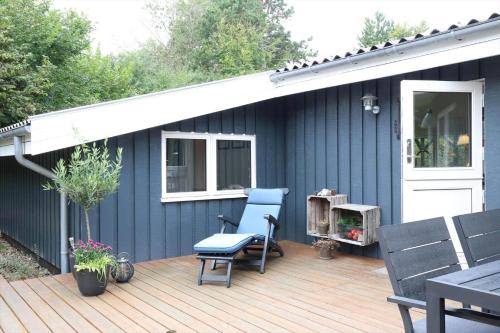 a blue house with a wooden deck with a chair at 13373-Asnaes-Radyrvej-24 in Asnæs