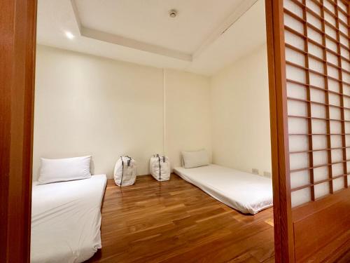 two beds in a room with white walls and wooden floors at Taihu Hotel Sun Moon Lake in Yuchi