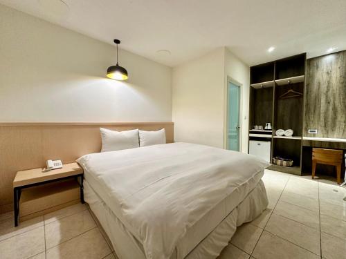 a bedroom with a large white bed and a bathroom at Taihu Hotel Sun Moon Lake in Yuchi