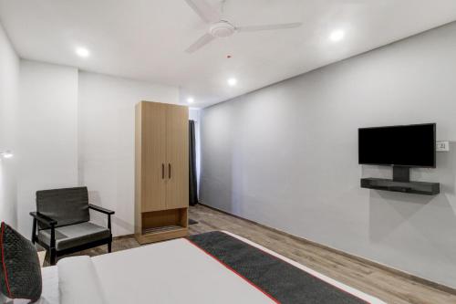 a room with a bed and a tv and a chair at Super Townhouse RCC Majestic 397 LB Nagar in Hyderabad