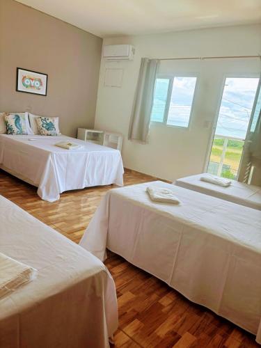 a room with two beds and a large window at Pousada sol e mar in Serra