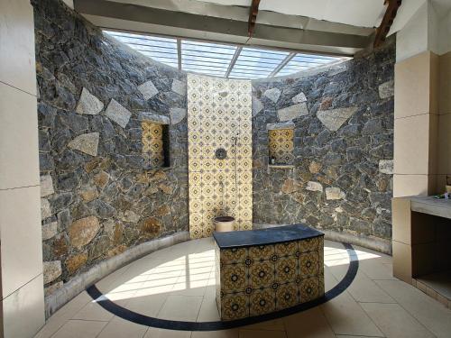 a room with a stone wall with a table in it at The Thatch in Auroville