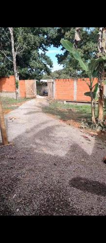 an empty road with an orange fence and trees at Raízes kit net in Itacaré