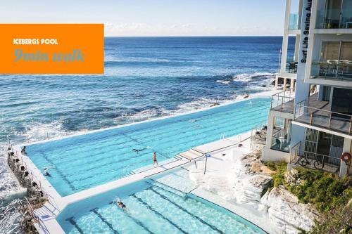 a swimming pool on the beach next to a building at Designer Bondi apartment - walk to beach! in Sydney