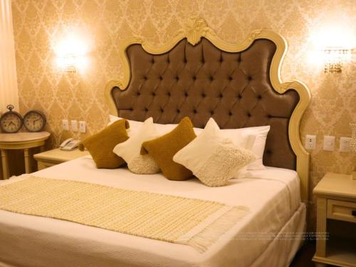 a bedroom with a bed with a large headboard and pillows at Hotel Embajada in San Luis Potosí
