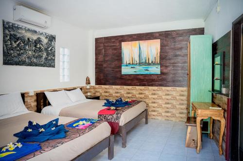 a room with two beds and a table and a desk at The Canda Hotel in Nusa Lembongan