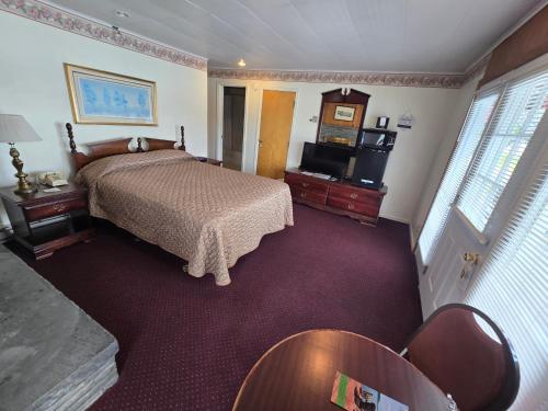 a bedroom with a bed and a tv in it at Lake View Motel in Cooperstown