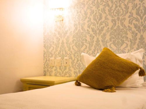 a bed with a yellow pillow sitting on top of it at Hotel Embajada in San Luis Potosí