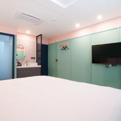 a bedroom with a white bed and a bathroom at 사천잠보호텔 in Sacheon