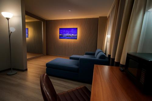 a living room with a blue couch and a painting at Hotel Pergola Jamaica JFK in Queens