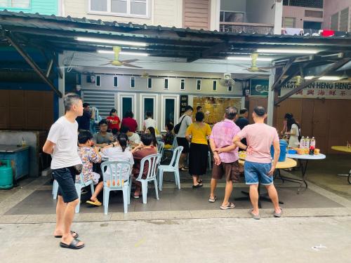 a group of people standing outside of a restaurant at 吉胆街坊民宿street Homes Inn Pulau Ketam in Bagan Pulau Ketam