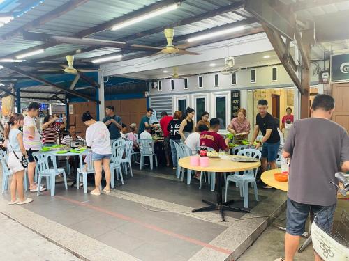 a group of people sitting at tables in a restaurant at 吉胆街坊民宿street Homes Inn Pulau Ketam in Bagan Pulau Ketam