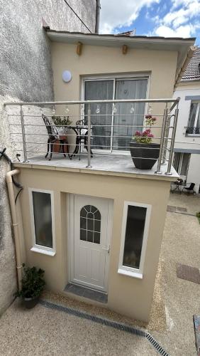 a house with a balcony with a door and a patio at Maisonnette neuve, centre-ville, 20mn de Paris in Herblay