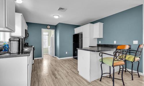 a kitchen with white cabinets and blue walls and chairs at Best Game Room, Kayaks, Steps To The Ocean in Seaside Heights