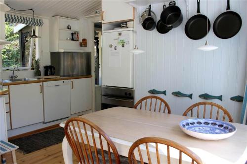 a kitchen with a table with chairs and pots and pans at 12255-Sjaellands-Odde-Klokkelyngvej-5 in Tjørneholm